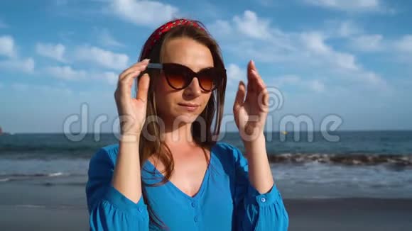 一个穿着漂亮蓝色裙子的狡猾女人在黑色火山海滩上的肖像视频的预览图
