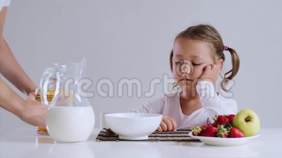 困倦的女孩开始吃她的玉米片和牛奶作为早餐视频的预览图