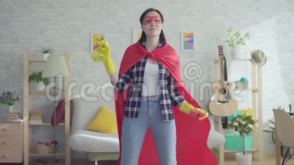 年轻女性家庭主妇超级英雄拿着抹布和喷雾器视频的预览图