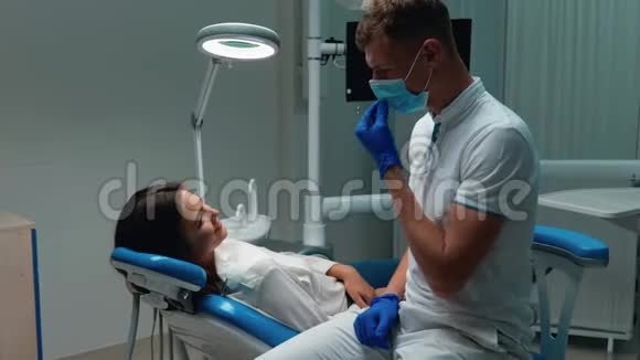 年轻的快乐医生牙医摘下他的口罩和手套给五个满意的结果病人都是女人视频的预览图