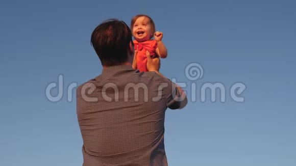爸爸把孩子扔在蓝天上爸爸和一个小女儿玩宝宝笑着高兴慢动作视频的预览图