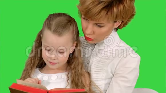 母亲和女儿在绿色屏幕上热情地阅读一本书Chroma键视频的预览图