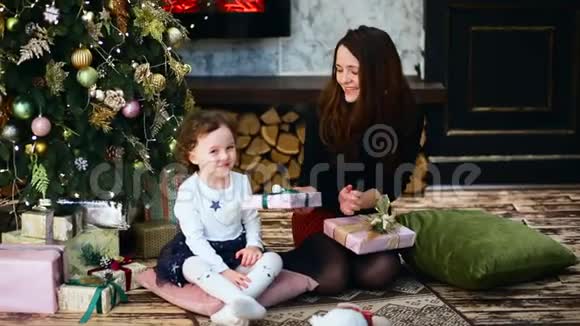 房间里母亲和女儿的膝部景色树上长满了圣诞树和礼物视频的预览图