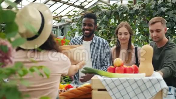 快乐的年轻人在市场上购买有机食品与女农民交谈视频的预览图
