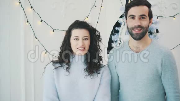 新年视频幼稚夫妇靠近圣诞树竖起大拇指和微笑视频的预览图