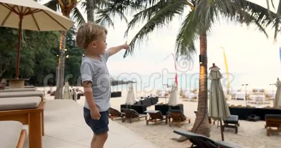 可爱的男孩在海滩上指着大海视频的预览图