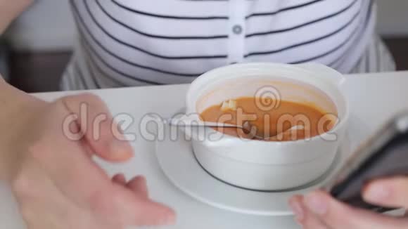 吃西班牙汤的女人看电话视频的预览图