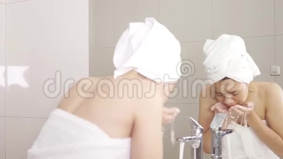 美丽的女人用水洗脸视频的预览图