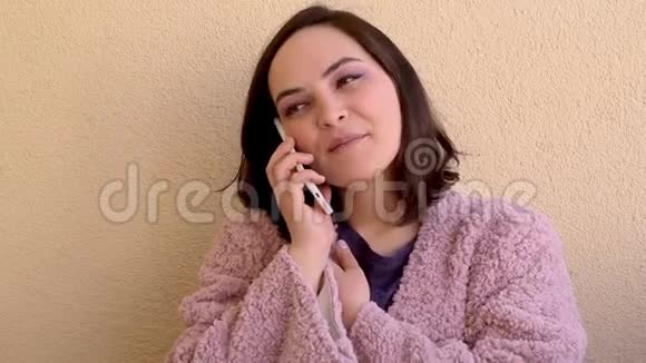 穿着粉红色外套的黑发女人在电话生活方式通信和技术概念上交谈视频的预览图