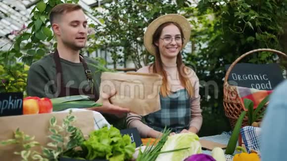 男人和女人把有机食品给顾客在农场市场上赚钱视频的预览图