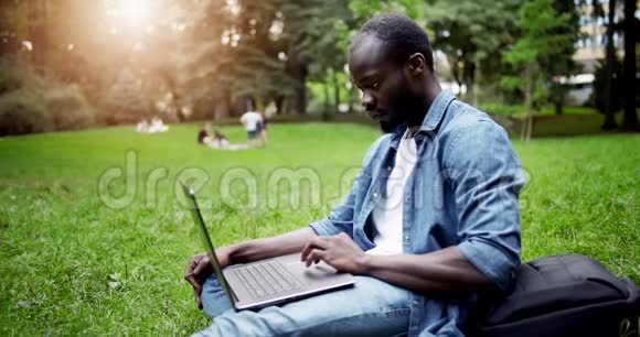 草坪日落时带笔记本电脑的非洲学生视频的预览图