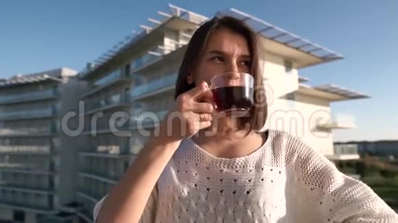 一个年轻漂亮的女孩在酒店的阳台上喝咖啡慢动作视频的预览图