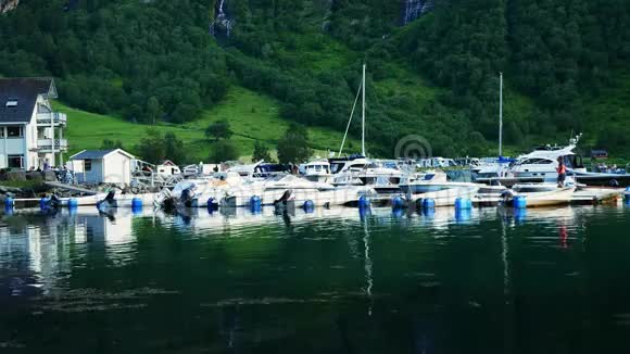 挪威吉兰格码头上一座陡峭的山峰附近许多游艇和它们在峡湾水域的倒影视频的预览图