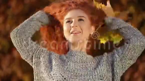 美丽的红发姑娘捧着一束美丽的黄秋叶视频的预览图
