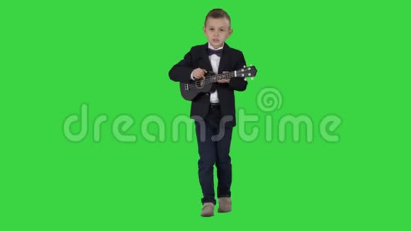 穿着服装的男孩在绿色屏幕上行走和演奏四弦琴Chroma键视频的预览图