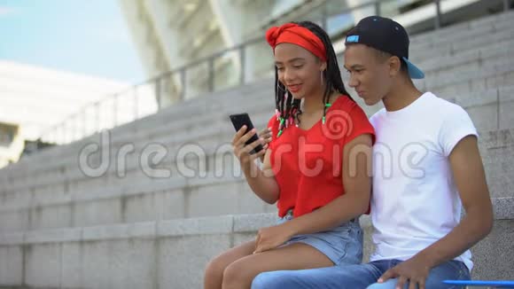 几个混血青少年坐在智能手机上的户外滚动网页视频的预览图
