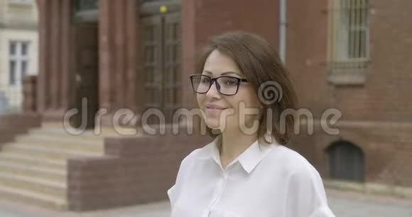 老师微笑的女人靠近学校大楼视频的预览图