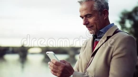 商人站在城市的桥梁上使用智能手机慢动作视频的预览图