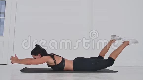 年轻有魅力的女人在双腿基克斯锻炼灰色工作室年轻有魅力的女人练习瑜伽伸展身体视频的预览图