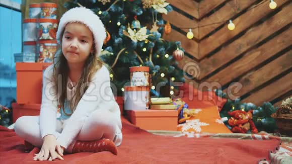 失望的小女孩穿着圣诞服装坐在洛托斯的位置上在木制的圣诞背景下皱眉视频的预览图