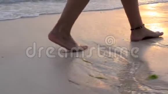 女腿沿着沙滩行走波浪在日落时冲走脚下的台阶光着脚的女孩慢镜头视频的预览图
