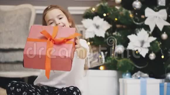特写广告视频小女孩得到了一个礼品盒并在圣诞节背景下呈现在镜头前视频的预览图
