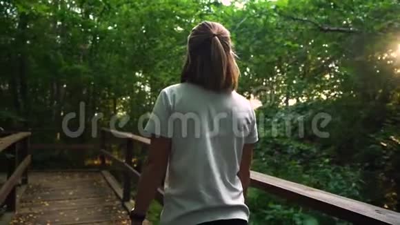 穿白色衬衫的漂亮苗条女孩走在树林里或公园前视频的预览图