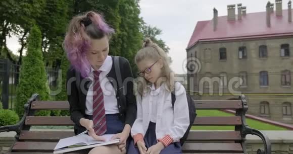 两个坐在长凳上的女学生小学生和高中生视频的预览图
