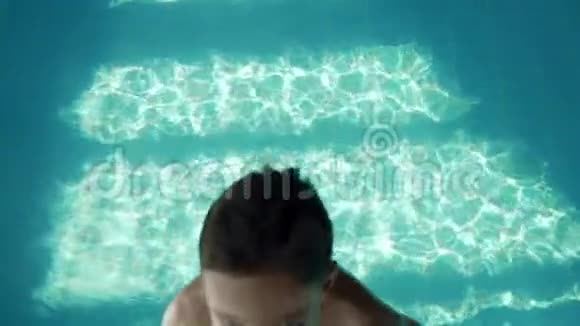 九岁的男孩掉进游泳池里带着蓝色的水溅向不同的方向飞行慢动作视频的预览图