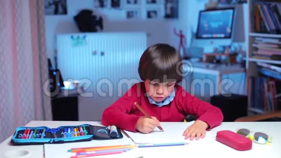 一个男孩坐在桌子旁在学校做绘画任务视频的预览图