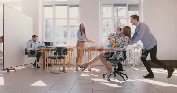 慢动作成功的女队长在办公室坐椅子有趣的商务人士一起庆祝成就视频的预览图