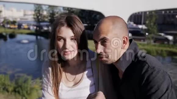 一个男人和一个女孩正坐在市中心的喷泉旁在炎热的夏日里聊天视频的预览图