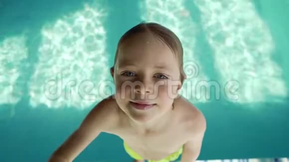 一个6岁的男孩带着蓝色的水掉进游泳池里溅向不同的方向飞行慢动作视频的预览图