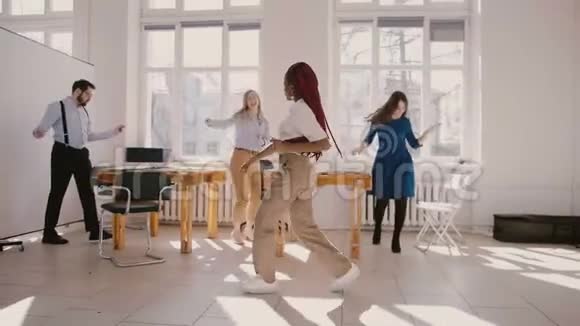快乐的年轻非裔美国女商人与同事一起跳疯狂的冠军舞庆祝成功视频的预览图