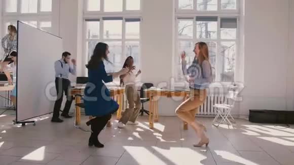 两个快乐的女性商业公司合作伙伴做有趣的赢家舞蹈庆祝与同事慢动作视频的预览图