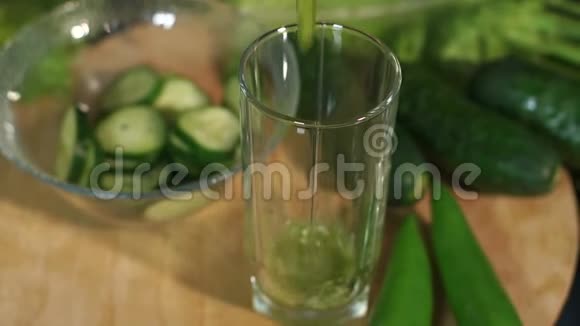 一个女人的特写镜头在黑色背景下的杯子里倒入一杯绿色的新鲜鸡尾酒视频的预览图