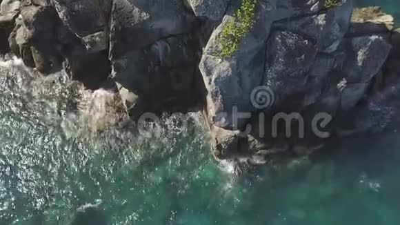 海浪飞溅到岩石悬崖无人机的视野透明的海浪在岩石悬崖上喷射泡沫空中破碎视频的预览图