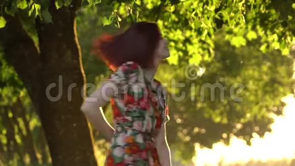 迷人的女孩在公园的夕阳下旋转慢速动作100磅射击视频的预览图