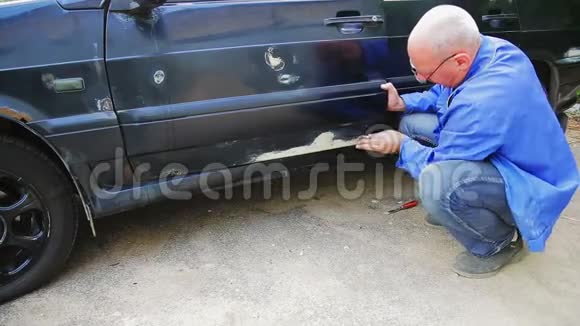 一个汽车修理工清理车身上生锈的座椅视频的预览图