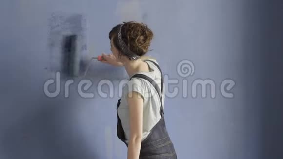 一个美丽的女人独自在墙上画蓝色的画视频的预览图