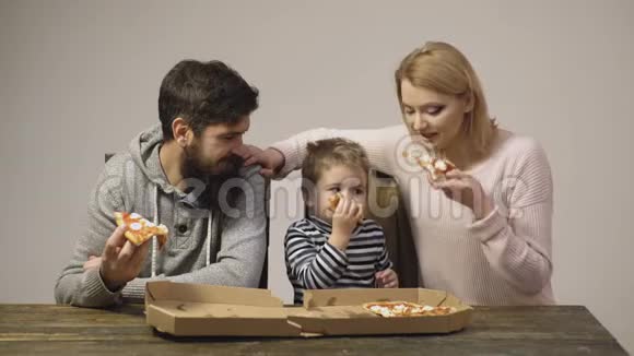美味的披萨带着父母吃披萨的小男孩饿孩子吃披萨营养概念视频的预览图