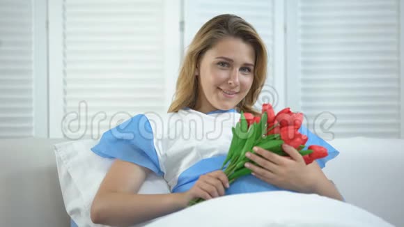 微笑的女人在医院里捧着一束郁金香孩子出生后在场视频的预览图