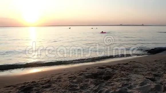 穿着彩色泳衣的漂亮女孩在日落时在海里游泳视频的预览图