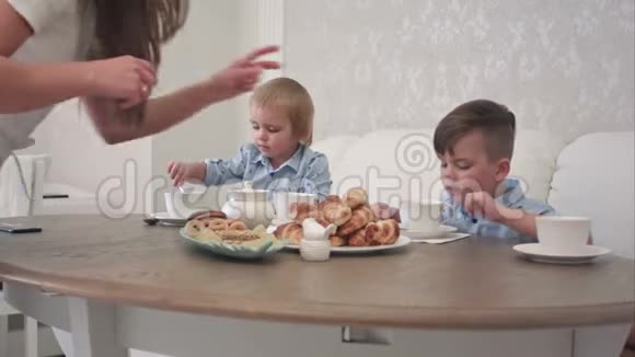 两个小男孩在桌旁喝着带有糕点的茶视频的预览图