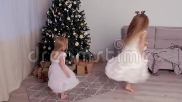 两个姐姐穿着漂亮的白色连衣裙在圣诞树附近跳舞视频的预览图