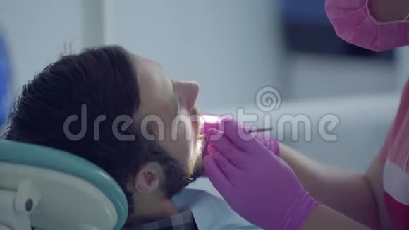 牙医戴着医用口罩和手套用医疗工具检查病人的牙齿女性专业医生视频的预览图