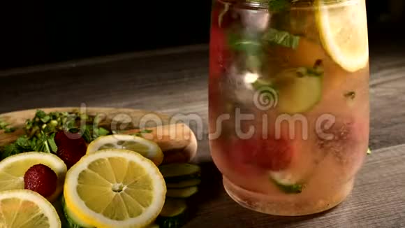 玻璃杯里的特写是柠檬和黄瓜片里面有薄荷和冷冻草莓视频的预览图