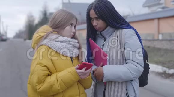 两个十几岁的朋友站在街上聊天非裔美国人和白人学生在户外交流视频的预览图
