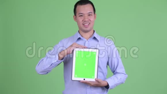 快乐的亚洲商人一边讲一边展示数码平板电脑视频的预览图