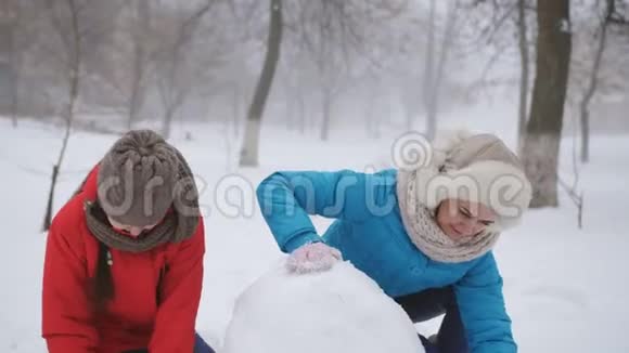 妈妈和两个女儿雕刻雪人一个幸福的家庭在冬天在外面堆雪人视频的预览图